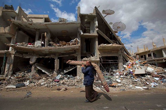 A Syrian man carries a carpet through a devastated part of the town of Palmyra. (Photo: AP) A Syrian man carries a carpet through a devastated part of the town of Palmyra. (Photo: AP)